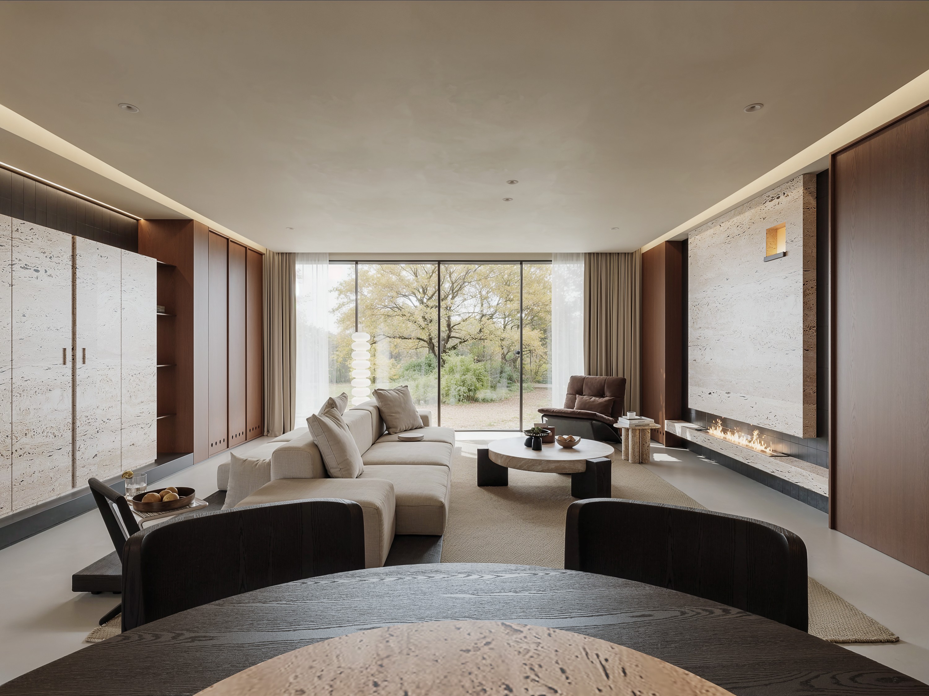 Warm minimalist living room with stone fireplace and garden view
